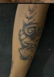 Aged black and gray ornamental tattoo on an arm