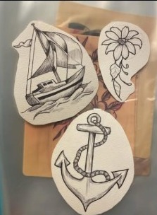 Tattoo flash designs including a sailboat, flower, and anchor